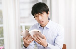 本を読み調べ物をする男性